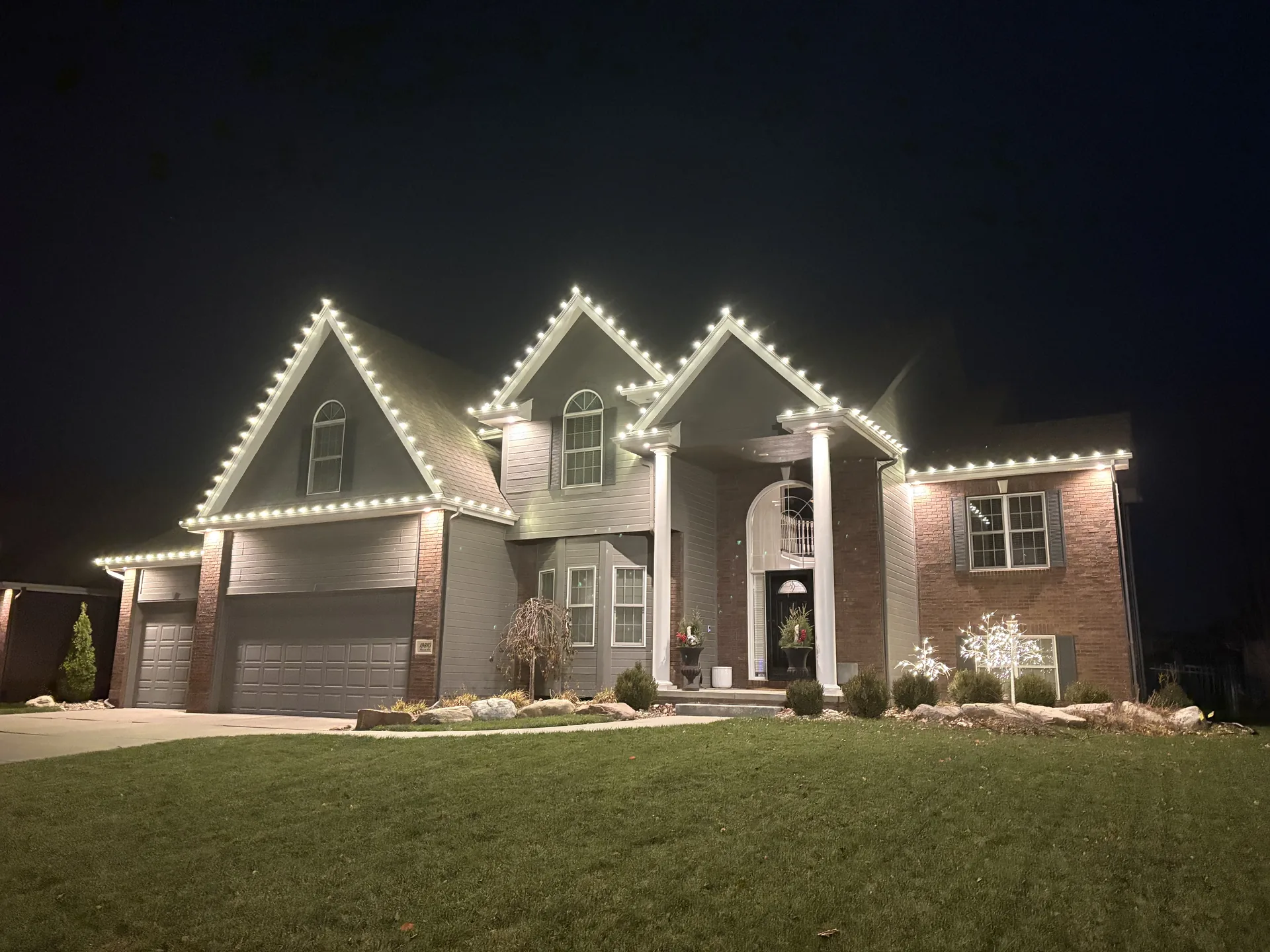 Home with warm white holiday lights installed along the roofline and porch