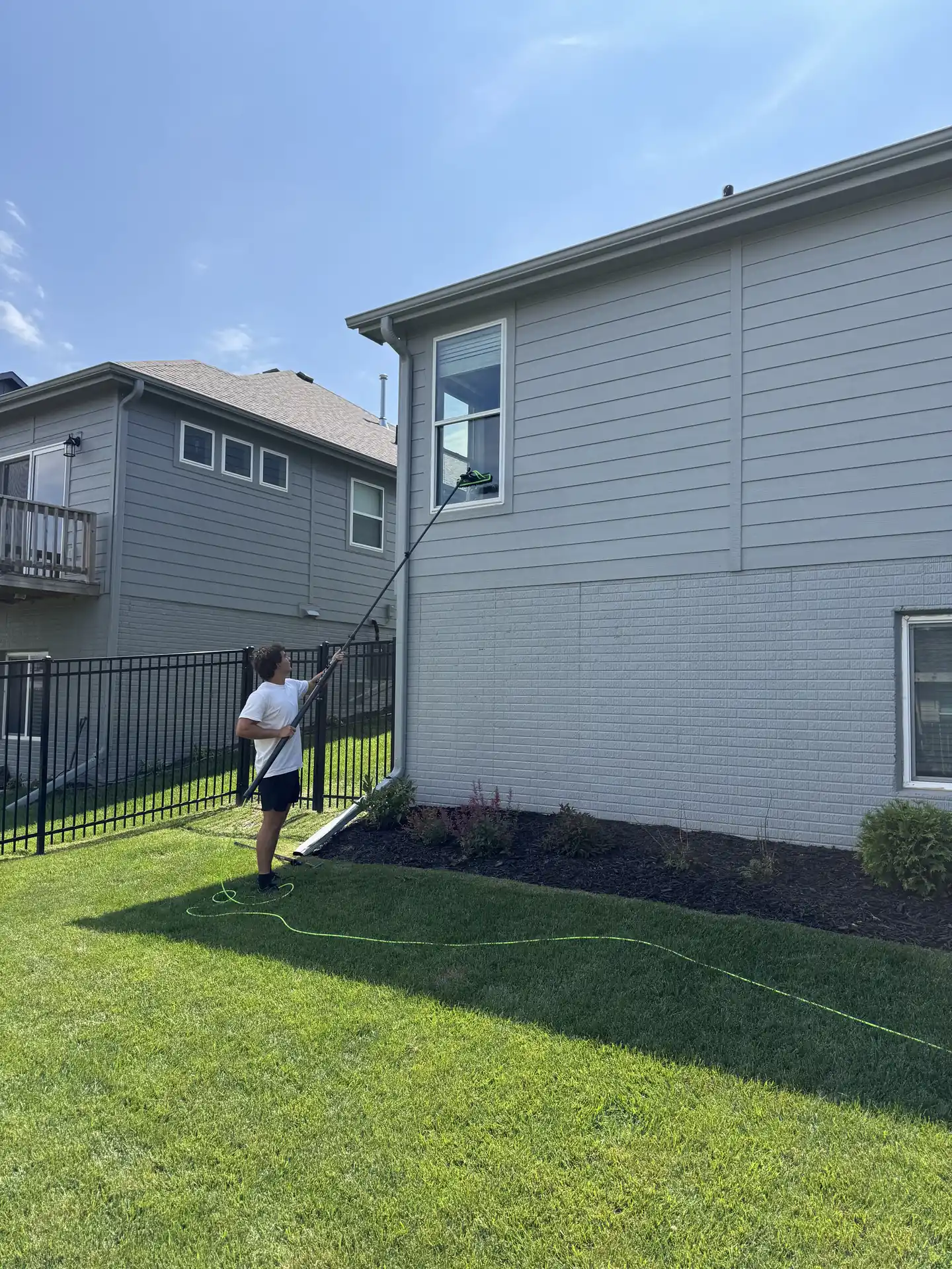 Technician walking equipment around the side of a customer's home
