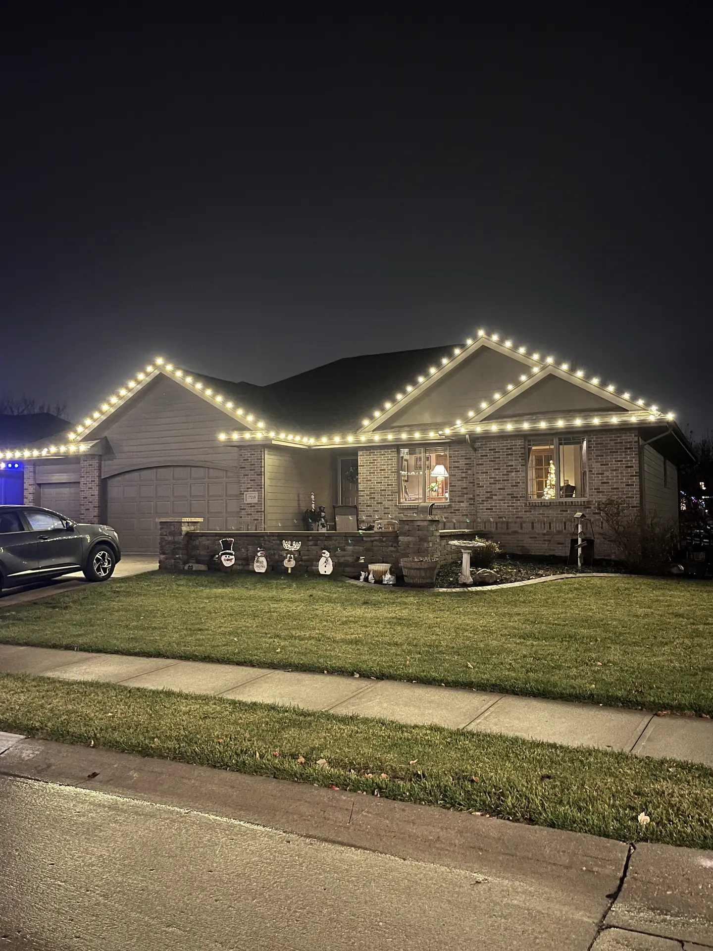 Illuminated rooflines and window trim at dusk on a brick home in Omaha, Nebraska — with the display glowing warm
