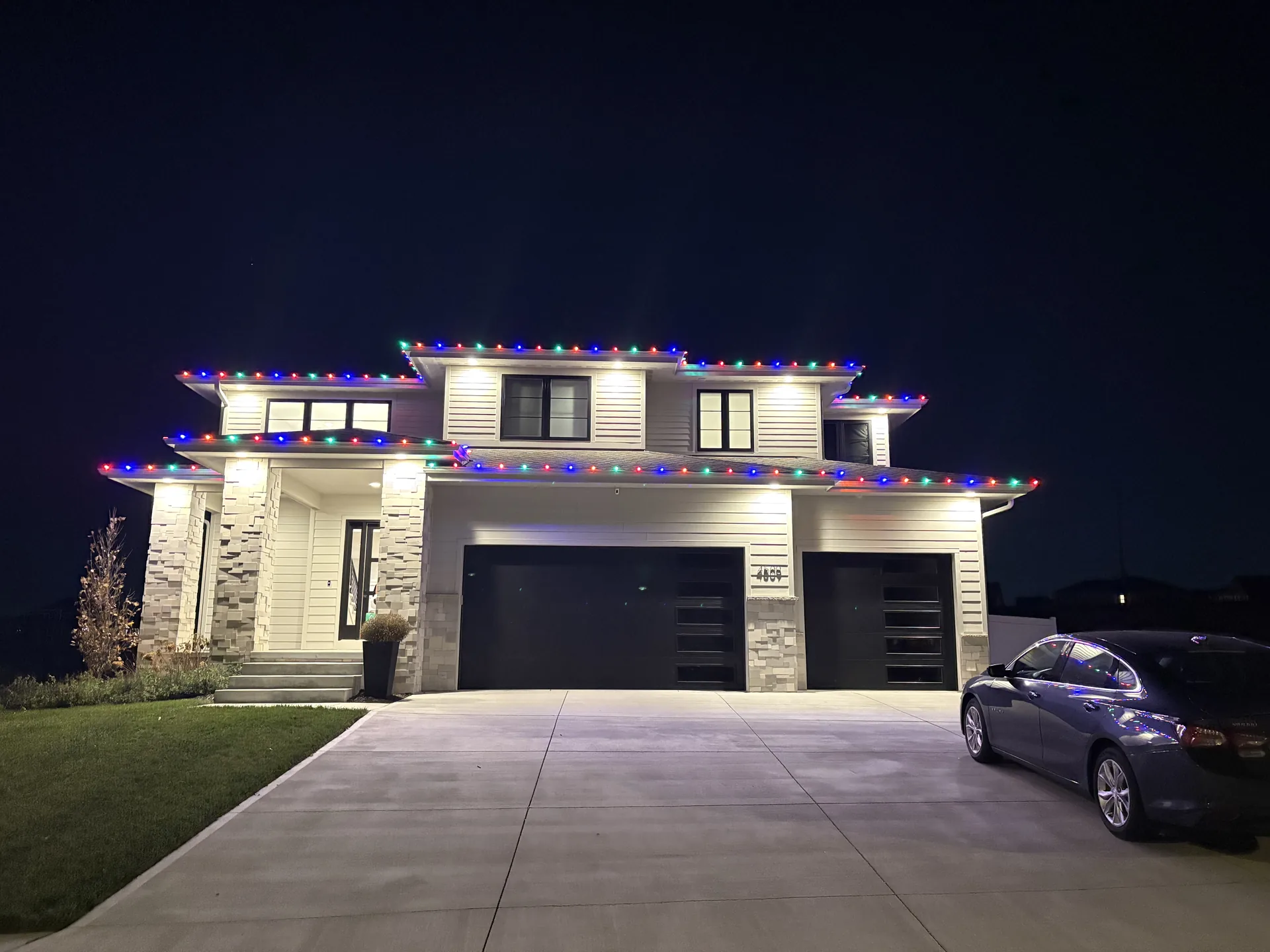 Modern home with multicolour holiday lights along the roof edge