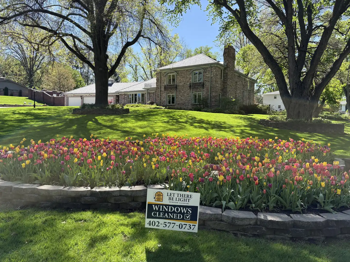 Company yard sign beside a tulip bed at a customer's property