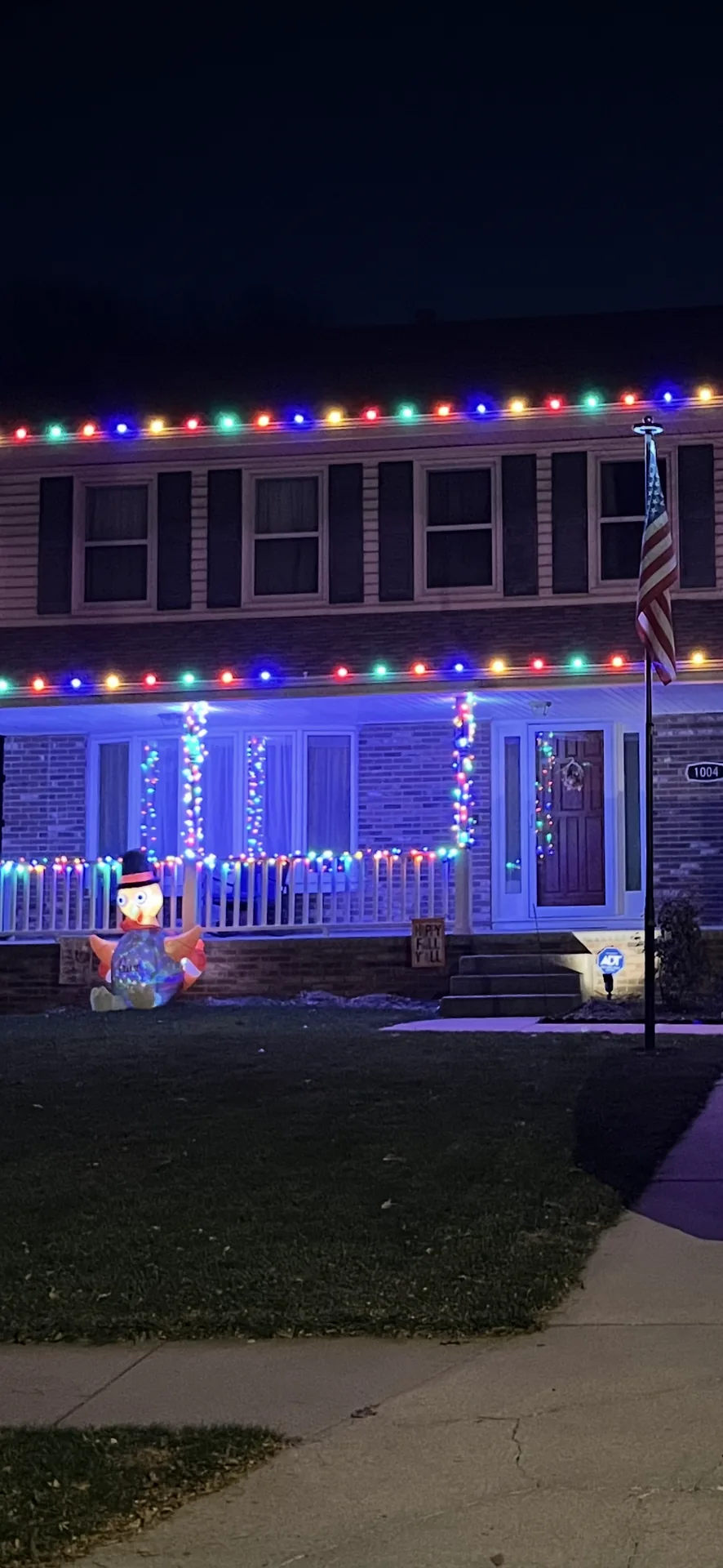 Tall multicolour holiday light installation on the front of a two-storey home