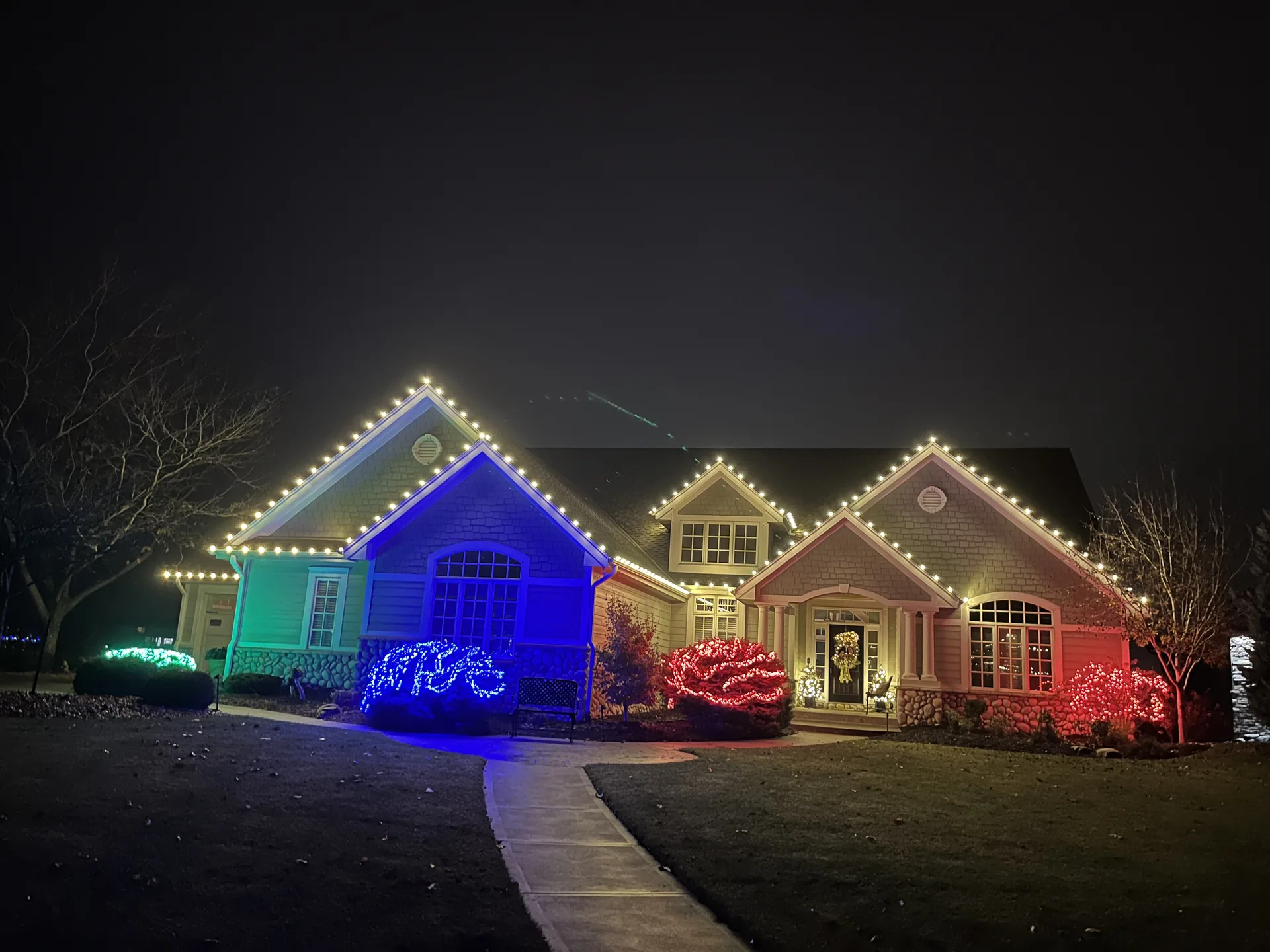 Home decorated with multicolour holiday lights along the roof and windows