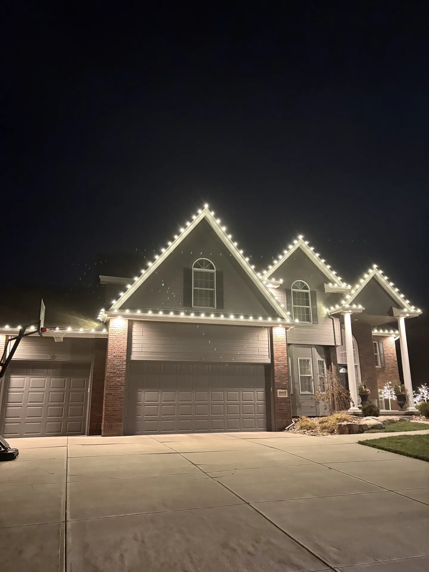 Evening view of a house outlined in warm white holiday lighting