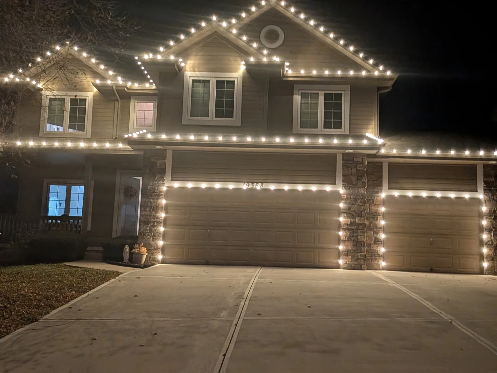 Warm white holiday lighting outlining the roofline on a brick home in Omaha, Nebraska — with the display glowing warm