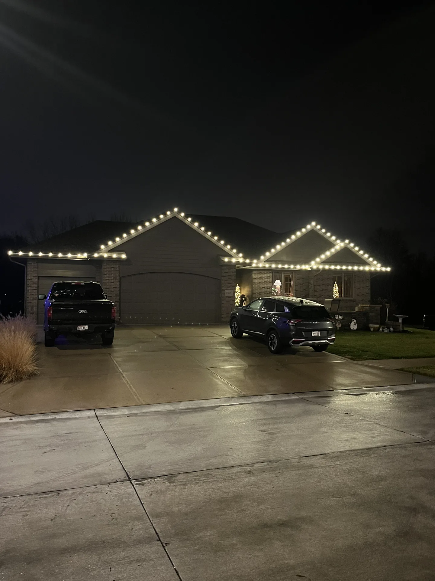 Warm white holiday lighting outlining the roofline on a two-story home in Omaha, Nebraska — with the display glowing warm