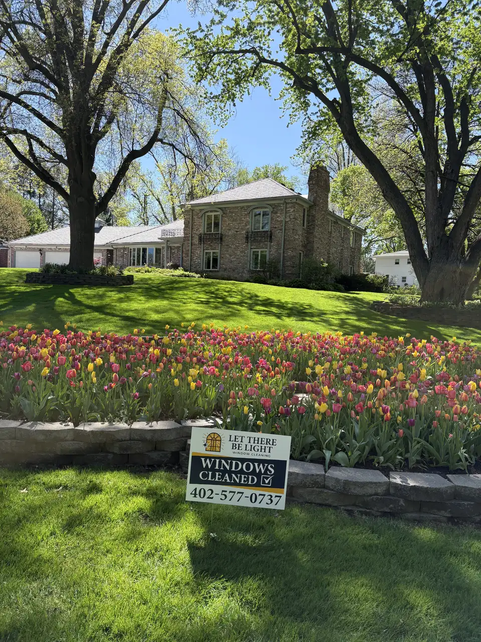 Branded Let There Be Light service vehicle on site on a two-story home in Omaha, Nebraska — with tracks and sills detailed