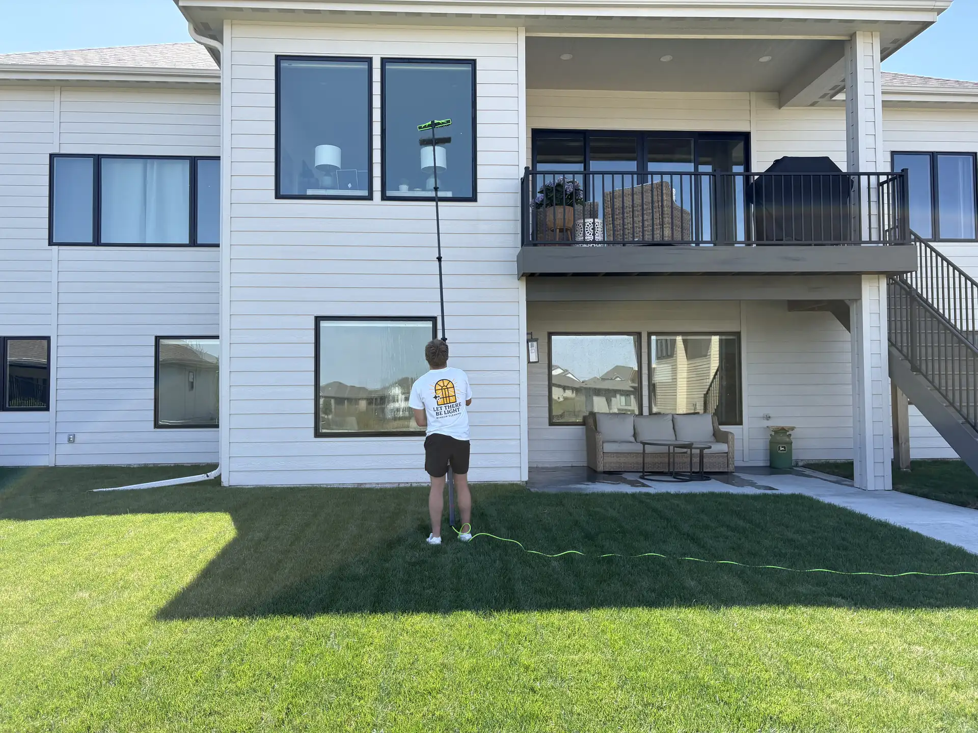 Water-fed pole cleaning tall windows without ladders in the landscaping