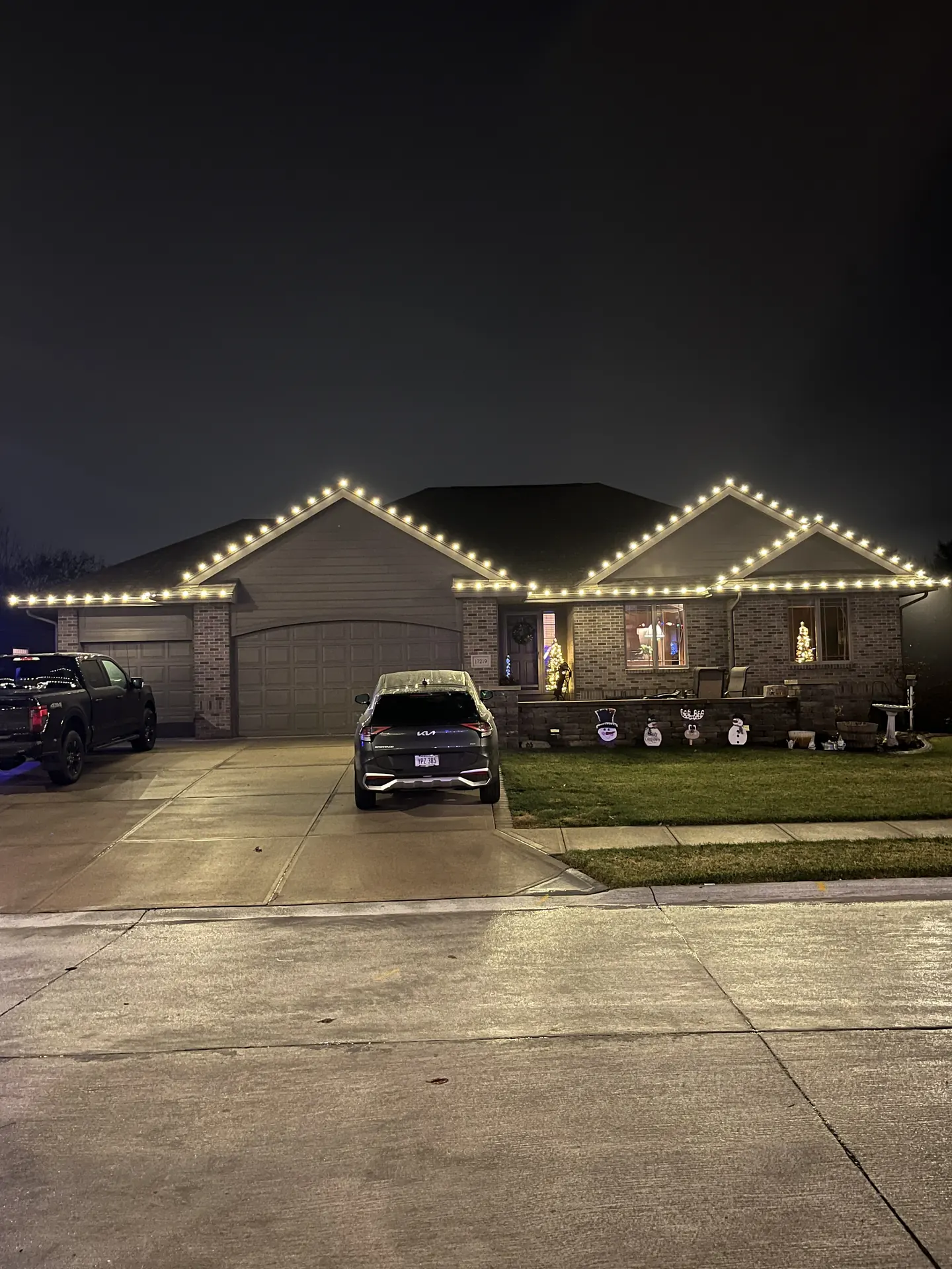 Warm white holiday lights outlining the roofline of a ranch-style Omaha home